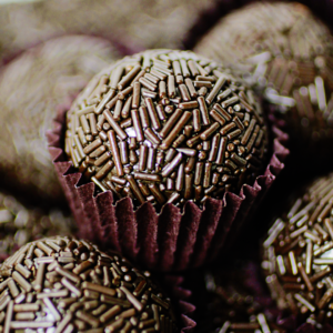 Brigadeiro de chocolate amargo confeitado com outros iguais no fundo da imagem.